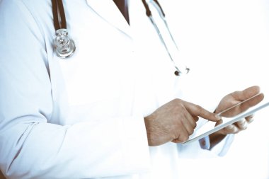 Doktor, ağ araştırması ya da sanal hastalık tedavisi için tablet bilgisayar kullanıyor. Eller yakın çekim. Klinikte mükemmel bir tıbbi hizmet. Modern tıp, tıbbi veri ve sağlık hizmetleri kavramları. Renkli resim.