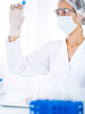 Koruyucu gözlüklü profesyonel kadın bilim adamı laboratuarda reaktörlerle araştırma tüpü kullanıyor. Tıp ve bilim araştırmaları kavramları.