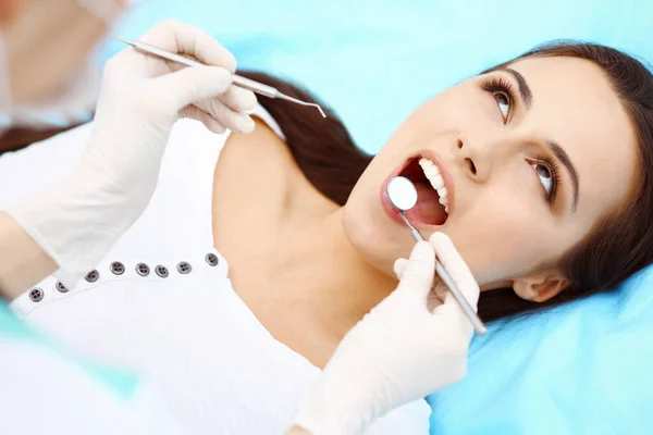 年轻女性病人到牙科诊所看病 在牙科诊所工作时 有健康直白牙齿的漂亮妇女坐在牙椅旁 张开嘴进行口腔检查 牙科诊所 口腔科概念 — 图库照片