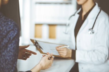 Doktor ve hasta klinikte otururken sağlık muayenesini tartışıyorlar. Hastanede mükemmel bir tıbbi hizmet.