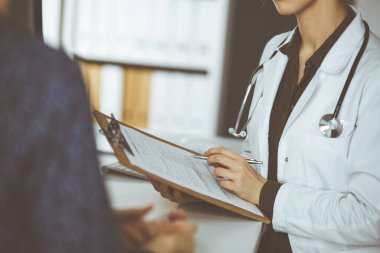 Doktor ve hasta klinikte otururken sağlık muayenesini tartışıyorlar. Hastanede mükemmel bir tıbbi hizmet..