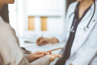 Doktor ve hasta klinikte otururken sağlık muayenesini tartışıyorlar. Hastanede mükemmel bir tıbbi hizmet..