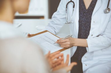 Doktor ve hasta klinikte otururken sağlık muayenesini tartışıyorlar. Hastanede mükemmel bir tıbbi hizmet..