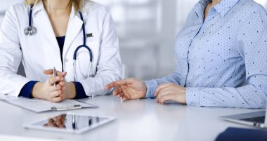 Bilinmeyen kadın. Doktor, klinikteki dolapta birlikte otururken hastasını dinliyor. Steteskoplu kadın doktor panoya yazı yazıyor, kapat. Hastanede mükemmel bir tıbbi hizmet. Tıp konsepti.