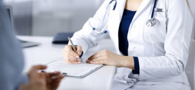 Bilinmeyen kadın doktor, bir klinikteki dolapta otururken hastasına bazı antibiyotikler yazıyor. Steteskoplu bir kadın doktor yakın plan panoda yazı yazıyor. Hastanede mükemmel bir tıbbi hizmet. İlaç.