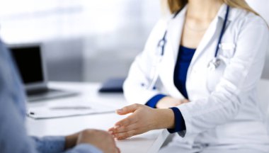 Bilinmeyen kadın-doktor bir klinikteki dolapta yan yana otururken hastasıyla konuşuyor. Steteskopu olan bir kadın doktor, yakın plan. Hastanede mükemmel bir tıbbi hizmet. Tıp konsepti.