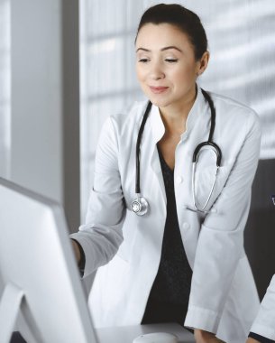 İki kadın hekim klinikteki masada dururken tıbbi terapiyi tartışıyorlar. Doktorlar işte bilgisayar kullanırlar. Tıpta takım çalışması