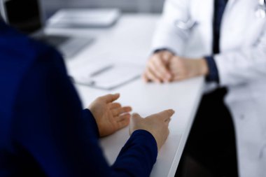 Bilinmeyen kadın-doktor, klinikteki dolapta birlikte otururken hastasıyla teşhisi hakkında konuşuyor. İşyerindeki doktor, yakın plan. Hastanede mükemmel bir tıbbi hizmet. Tıp konsepti.
