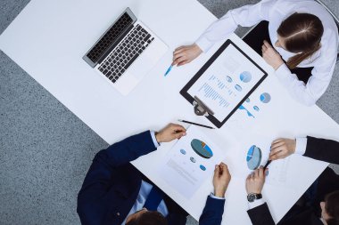 Bir grup iş adamı mali belgeleri analiz ediyor, yukarıdan bakıyorlar. İş ekibi toplantıda..