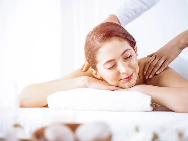 Hermosa mujer morena disfrutando de masaje de espalda en el centro de spa soleado. Concepto de belleza y medicina — Foto de Stock