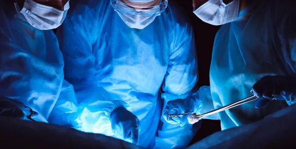安全マスクを着用した外科医のグループが手術を行う。医学の概念 — ストック写真