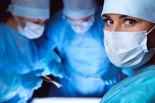 Grupo de cirurgiões usando máscaras de segurança realizando operação. Conceito de medicina — Fotografia de Stock