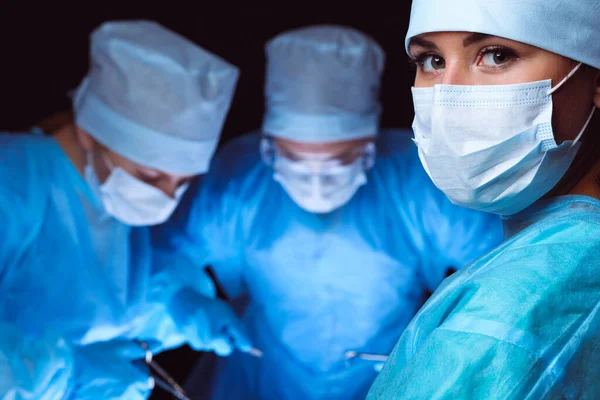 Group of surgeons wearing safety masks performing operation. Medicine concept — Stock Photo, Image