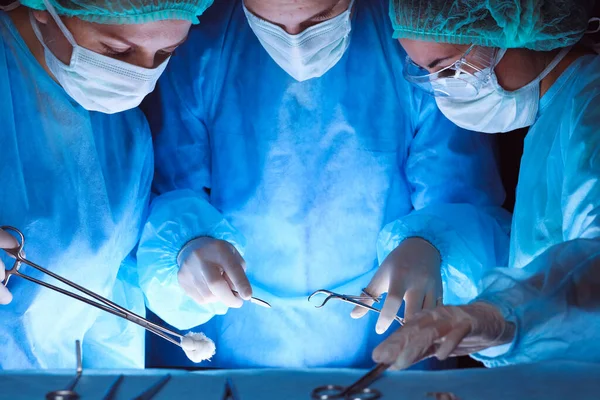 Skupina chirurgů, kteří nosí bezpečnostní masky a provádějí operace. Detailní záběr chirurgických nástrojů. Koncept medicíny — Stock fotografie