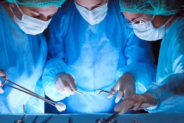 Group of surgeons wearing safety masks performing operation. Close-up of surgery tools. Medicine concept — Stock Photo, Image