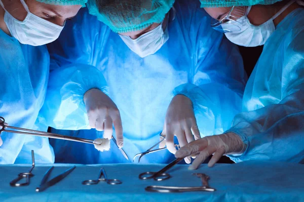 Grupo de cirurgiões usando máscaras de segurança realizando operação. Close-up de ferramentas de cirurgia. Conceito de medicina — Fotografia de Stock