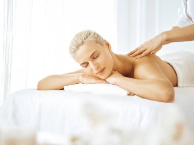 Güzel sarışın kadın kapalı gözlerle sırt masajından hoşlanıyor. Spa salonu konsepti