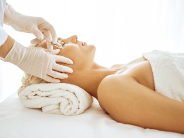 Güzellik uzmanı elleri şırıngayla kadın yüzüne güzellik prosedürü uyguluyor. Kozmetik tıp ve cerrahi, güzellik enjeksiyonları konsepti