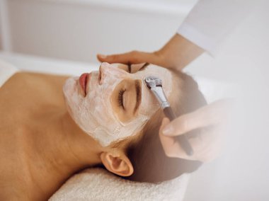 Güzel esmer kadın kapalı gözlerle kozmetik maske takmaktan zevk alıyor. Tıp ve kaplıca merkezi kavramlarında rahatlatıcı tedavi