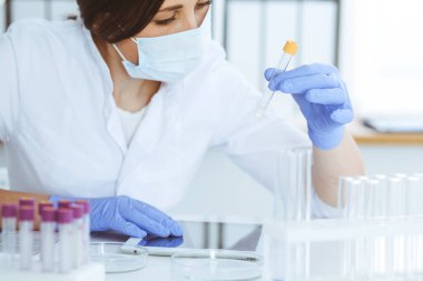 Koruyucu gözlüklü profesyonel kadın bilim adamının laboratuvarda reaksiyonlarla ya da kan testiyle deney yapması. Tıp, biyoteknoloji ve araştırma konsepti.