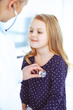 Doktor steteskopla çocuk bir hastayı muayene ediyor. Doktor randevusunda tatlı bir kız bebek. Tıp konsepti. Renkli fotoğraf