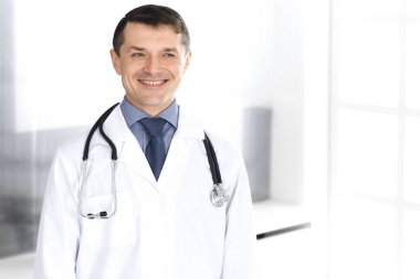 Doktor neşeli bir şekilde kameraya gülümsüyor. Klinikte mükemmel bir tıbbi hizmet. Tıp ve sağlık sektöründe mutlu bir gelecek