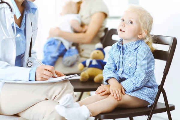 Gelukkige glimlachende kindpatiënt bij gebruikelijke medische inspectie. Dokter en patiënt in de kliniek. Geneeskunde, gezondheidsconcepten — Stockfoto