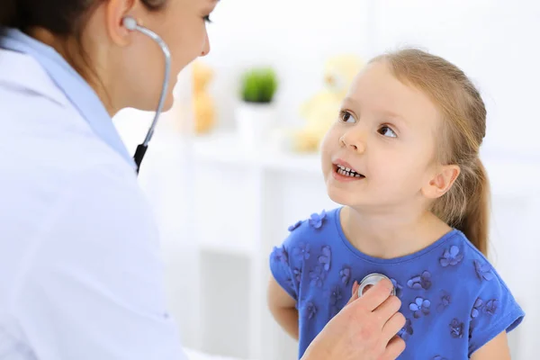 Doutor examinando uma menina por estetoscópio. Paciente de criança sorridente feliz em inspeção médica habitual. Conceitos de medicina e saúde — Fotografia de Stock