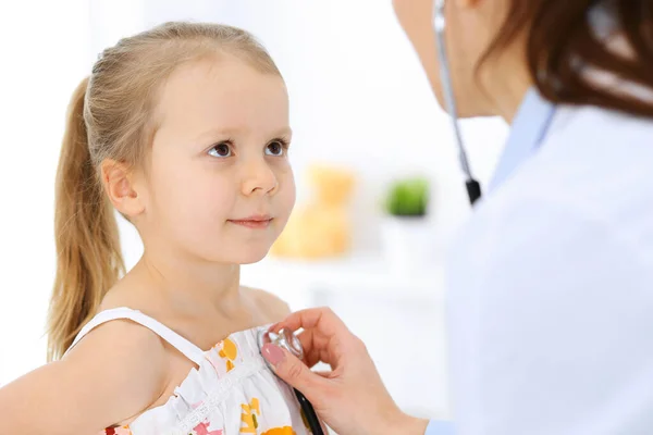 医生用听诊器检查一个小女孩.在通常的医疗检查中快乐地微笑着的儿童病人。医药和保健概念 — 图库照片