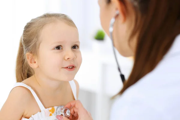 Dokter die een klein meisje onderzoekt met stethoscoop. Gelukkige glimlachende kindpatiënt bij gebruikelijke medische inspectie. Begrippen geneeskunde en gezondheidszorg — Stockfoto