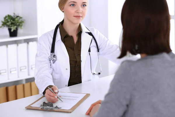Hastane muayenehanesindeki genç kadın doktor ve hasta. Haki renkli terapist bluzu iyi görünüyor. Tıp, sağlık ve doktor randevu kavramı — Stok fotoğraf