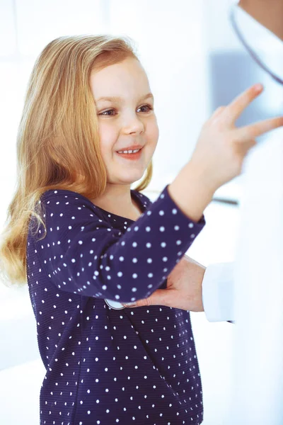 Médico examinando a un niño paciente por estetoscopio. Linda niña en la cita con el médico. Concepto de medicina. Foto tonificada — Foto de Stock