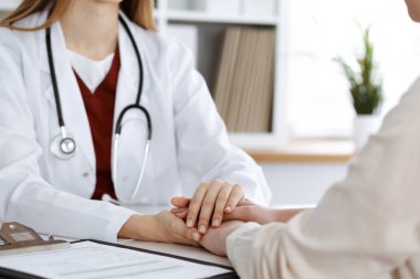 Kadın hastasına güvence veren kimliği belirsiz kadın doktorun elleri, yakın plan. Tıp konsepti