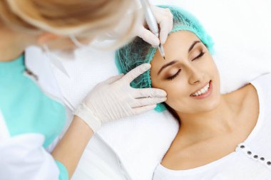 Kadın yüzüne kaş dövmesi yapan profesyonel bir güzellik uzmanı. Güzellik salonunda kalıcı kaş makyajı, yakın çekim. Kozmetoloji tedavisi