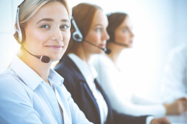 Kulaklıklı, güler yüzlü iş kadını müşterilere danışıyor. Sunny Office 'de çalışan çeşitli telefon operatörleri. Çağrı merkezi ve iş adamları kavramı.
