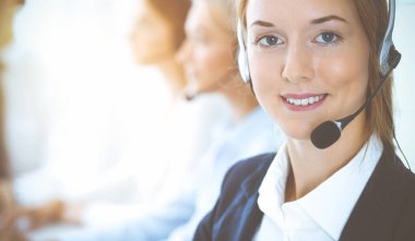 Kulaklıklı, güler yüzlü iş kadını müşterilere danışıyor. Sunny Office 'de çalışan çeşitli telefon operatörleri. Çağrı merkezi ve iş adamları kavramı.