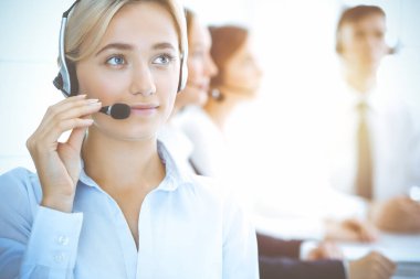 Kulaklıklı, güler yüzlü iş kadını müşterilere danışıyor. Sunny Office 'de çalışan çeşitli telefon operatörleri. Çağrı merkezi ve iş adamları kavramı.