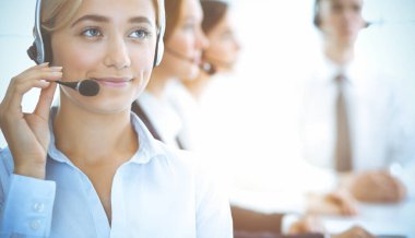 Kulaklıklı, güler yüzlü iş kadını müşterilere danışıyor. Sunny Office 'de çalışan çeşitli telefon operatörleri. Çağrı merkezi ve iş adamları kavramı.