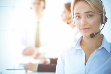 Kulaklıklı, güler yüzlü iş kadını müşterilere danışıyor. Sunny Office 'de çalışan çeşitli telefon operatörleri. Çağrı merkezi ve iş adamları kavramı.