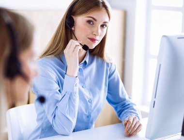 Çağrı merkezi operatörünün portresi. Kulaklık takmış bir grup insan müşterilere yardım etmeye hazır. İş konsepti