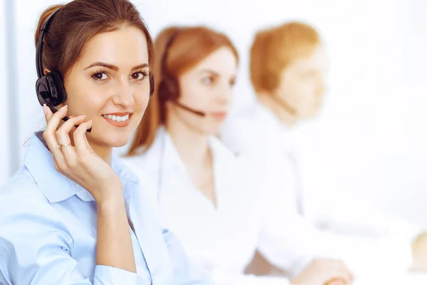 Call center operators. Focus on beautiful business woman using headset in sunny office — Stock Photo, Image