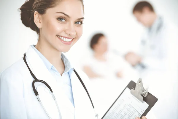 Alegre mujer-médico sonriente en el fondo de su paciente en la cama. Concepto de medicina — Foto de Stock