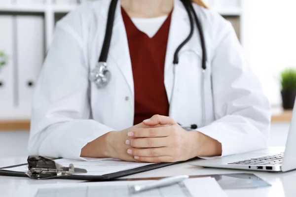 Mujer-médico desconocido sentado en la mesa en el lugar de trabajo, primer plano de las manos. Concepto de medicina — Foto de Stock
