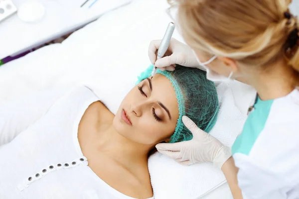 Professionele schoonheidsspecialiste die wenkbrauwtatoeage doet op vrouwengezicht. Permanente make-up in schoonheidssalon, close-up. Cosmetologische behandeling — Stockfoto