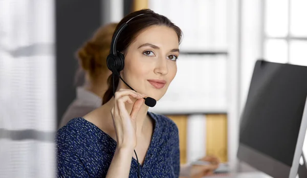 Amable mujer de negocios asiática o latinoamericana hablando por auriculares en la oficina. Centro de llamadas y grupo de personas diversas en los negocios —  Fotos de Stock
