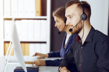 Günümüz güneşli ofisinde otururken, kulaklıkla konuşan kızıl sakallı bir iş adamı. Çağrı merkezinde çeşitli insanlar grubu