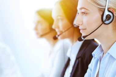 Güneşli ofiste çalışan bir grup farklı telefon operatörü. Kulaklıklı yakışıklı iş kadını müşterilere danışıyor. Çağrı merkezi ve iş adamları kavramı
