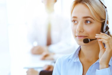 Güneşli ofiste çalışan bir grup farklı telefon operatörü. Kulaklıklı yakışıklı iş kadını müşterilere danışıyor. Çağrı merkezi ve iş adamları kavramı