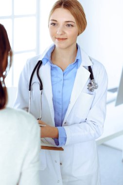 Hastane muayenehanesindeki genç kadın doktor ve hasta. Terapistin mavi renkli bluzu iyi görünüyor. Tıp ve sağlık hizmetleri kavramı