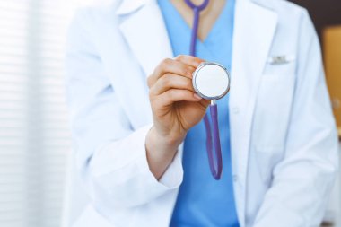 Bilinmeyen doktor kadın steteskop başı tutuyor, yakın plan. Doktor hastayı muayene etmeye ve yardım etmeye hazır. Sağlık hizmetleri, en iyi tedavi ve tıp konseptinde yardım ve sigorta